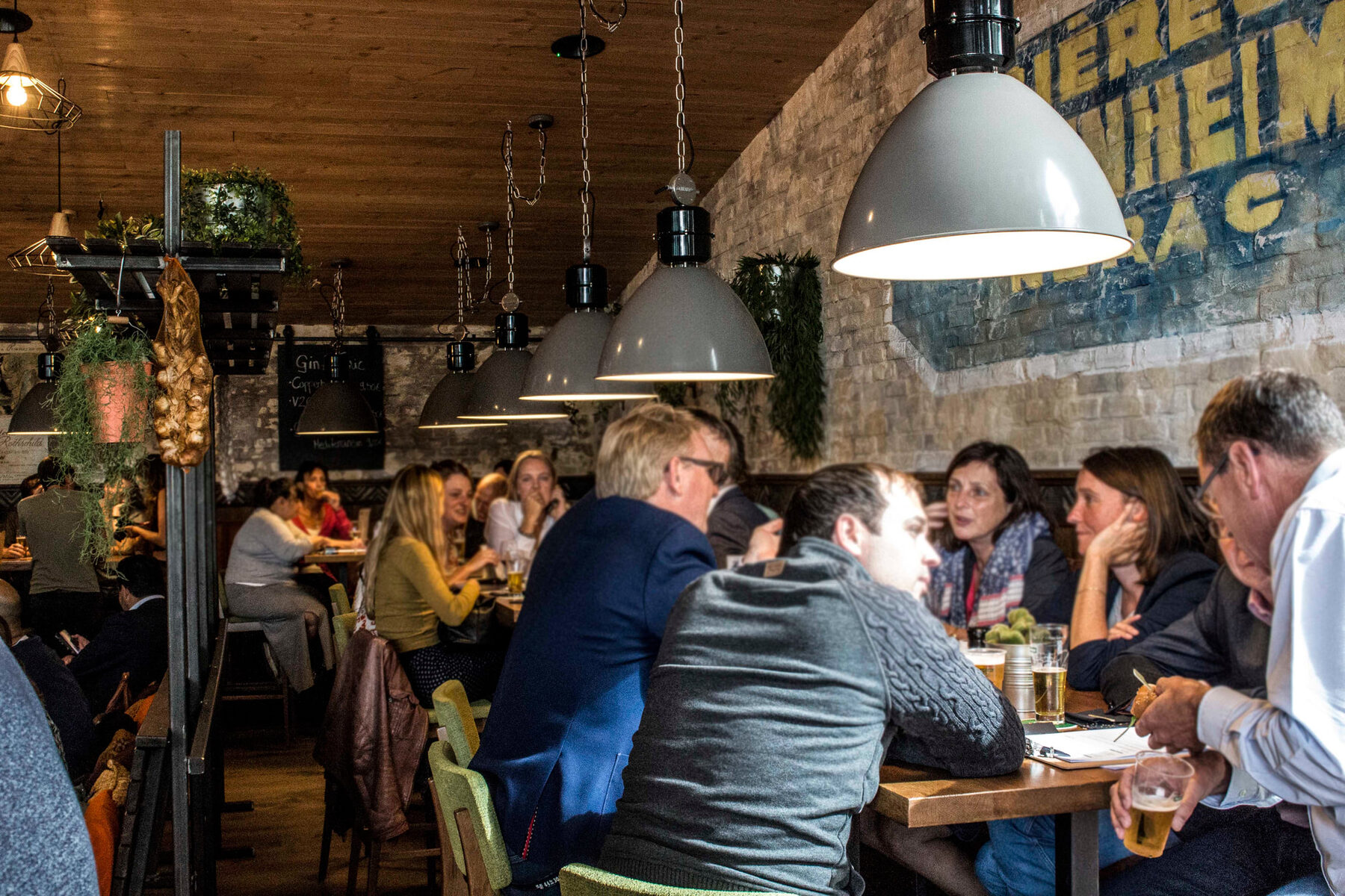 Gasten aan tafel onder de industriële lampen bij Helden